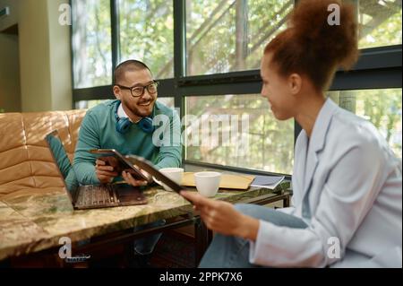 Businessman laughing with colleague while working together in coworking space Stock Photo