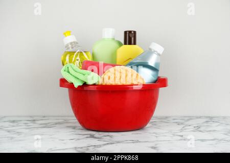 Red basin with cleaning products on marble table Stock Photo