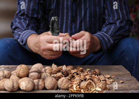 Man cracking walnuts at wooden table, closeup Stock Photo
