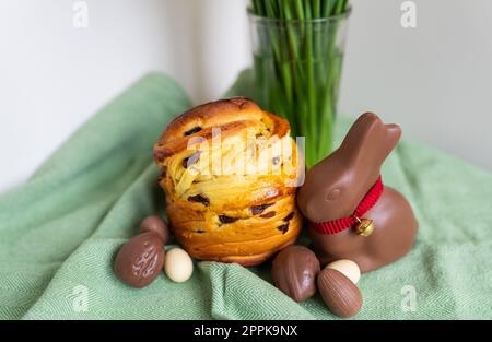 Homemade Easter traditional pastries lie on a green napkin with a bouquet of flowers, a rabbit, chocolate eggs. Easter baking and decoration. Stock Photo