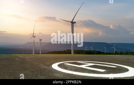 Asphalt helipad and wind farm. Wind energy. Wind power. Sustainable, renewable energy. Wind turbines generate electricity. Platform for helicopters and powered lift aircraft. Heliport of helicopter. Stock Photo