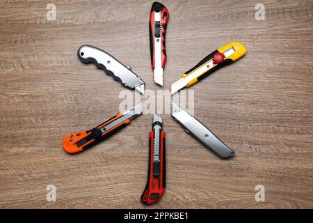 Many different utility knives on wooden table, flat lay Stock Photo