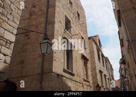 Dubrovnik, Croatia, 08.14. 2022. Narrow streets of the ancient town. The facades of the houses are made of marble and stone very close to each other. Windows with shutters. Summer tourism in Adriatic. Stock Photo