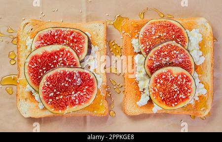 Sourdough wheat toast with ricotta cheese, fresh figs with honey and sesame seeds layout on craft paper backing. Top view of toast with figs.Breakfast Stock Photo