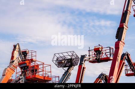 Articulated boom lift. Aerial platform lift. Telescopic boom lift against blue sky. Mobile construction crane for rent and sale. Maintenance and repair hydraulic boom lift service. Crane dealership. Stock Photo