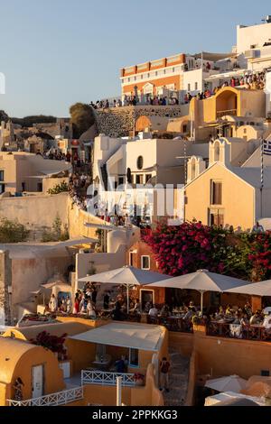 Whitewashed houses and windmills in Oia in warm rays of sunset on Santorini island. Greece Stock Photo