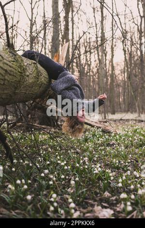 Laughing woman hanging on fallen tree scenic photography Stock Photo