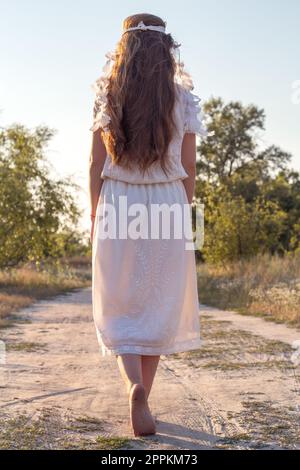 Close up beautiful barefoot woman in white dress strolling concept photo Stock Photo