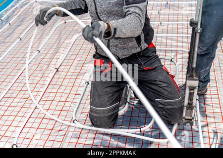 manual installation of underfloor heating in a new building. professional worker Stock Photo