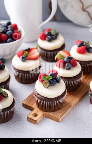 Chocolate cupcakes with cream cheese frosting and fresh summer berries Stock Photo