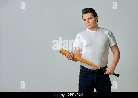 a man on a gray background holds a bat in his hands Stock Photo