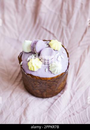 A traditional paska decorated with white Swiss chocolate and meringue stands on a lavender tablecloth. Easter holiday. Stock Photo