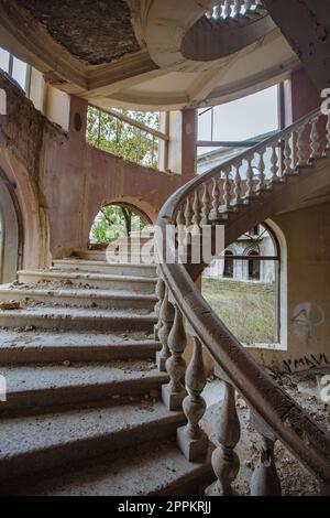 Old abandoned mansion with decorated spiral staircase. Stock Photo