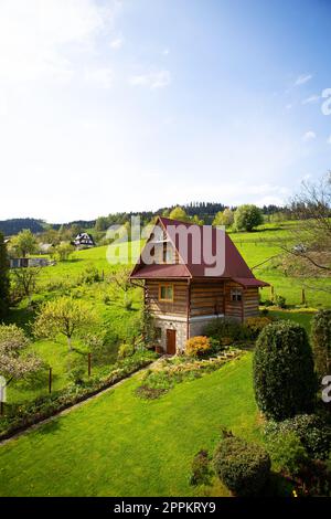 Old wooden cottage in a valley on a hill, beautiful blue sky. Landscaping. View from the window. Stock Photo