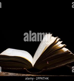 Old book open on vintage table on dark background. Stock Photo