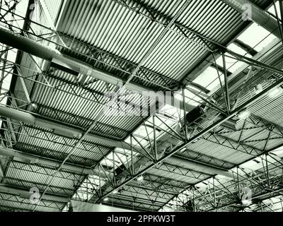 The roof of a hangar, a production hall or a sports hall. Metal structures, beams, supporting elements. Ventilation systems in large halls and rooms. Skylights. Industrial interior. Stock Photo