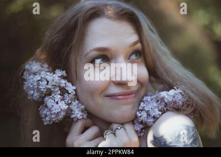 Close up happy woman pressing lilac stems to face portrait picture Stock Photo
