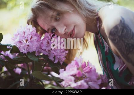 Close up woman bending head over pink flowering shrub portrait picture Stock Photo