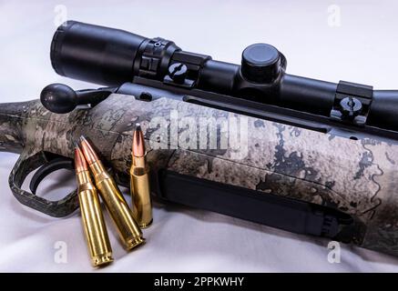 A high power deer rifle with a camo synthetic stock and three bullets on a white background Stock Photo