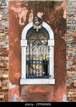 outdoor statue of Madonna behind bars in wall Stock Photo