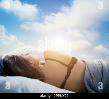 Girl sleeps in a cozy bed during sunrise. Concept of relax and rest. Stock Photo