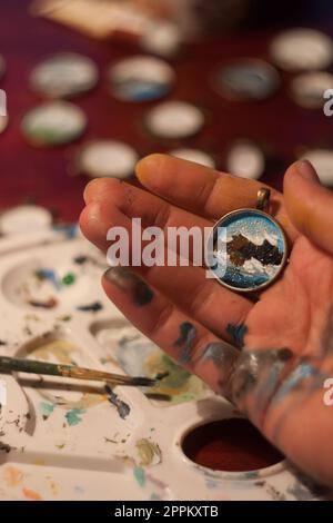 Close up artist drawing mountains on pendant concept photo Stock Photo