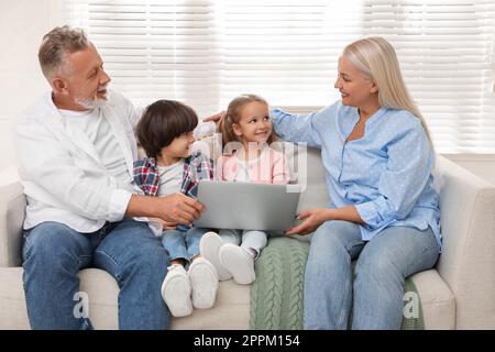 Happy grandparents spending time with grandchildren at home Stock Photo