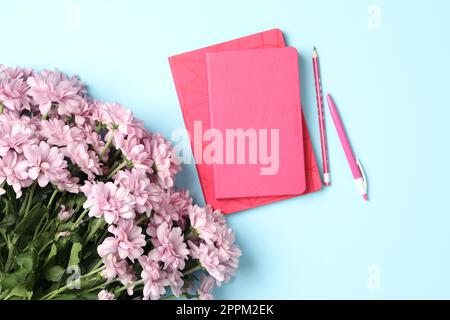 Different school stationery and beautiful pink flowers on light blue background, flat lay. Happy Teacher's Day Stock Photo