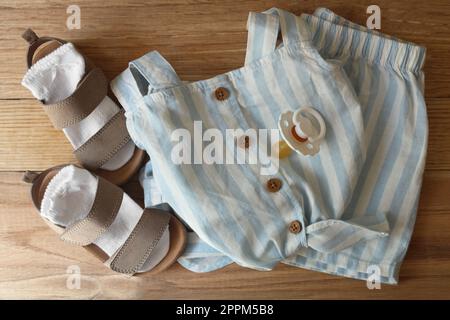 Stylish child clothes, shoes and accessories on wooden background, flat lay Stock Photo