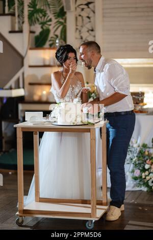 newlyweds happily cut and taste the wedding cake Stock Photo