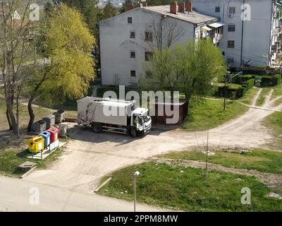 Sremska Mitrovica, Serbia, June 1, 2020. Garbage truck on the city street. Municipal and city services. Waste management and disposal. Car pulling up at the trash cans Stock Photo