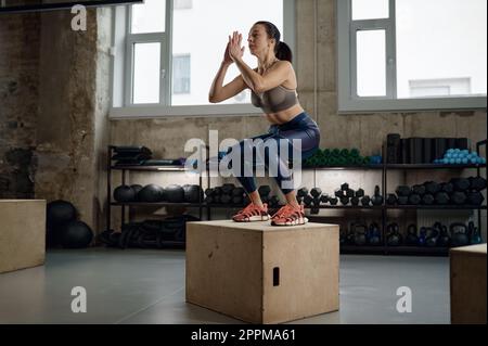 Strong muscular woman practicing sports with fitness box at gym Stock Photo