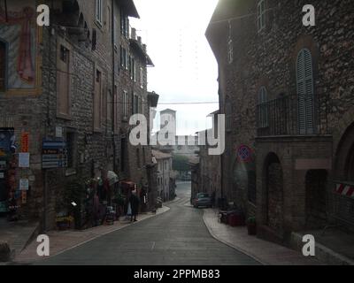 Assisi, Italy, December 10, 2020. Streets of Assisi, along which a group of tourists walk. Ancient buildings, close to each other. People on excursions. Narrow street Stock Photo