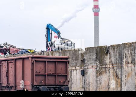 a stack of iron loaded on a train and a smoking chimney Stock Photo