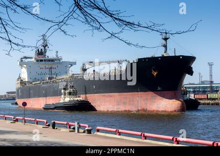 Three tug-boots pushing big ship Stock Photo