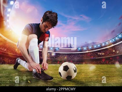 Soccer player ties his football shoes ready to play at the stadium Stock Photo