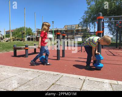 Sremska Mitrovica, Serbia. June 6, 2020. Flip-flops, weight lifting and weights, strength exercises. Two teenagers go in for sports on simulators, children on a sports ground Stock Photo