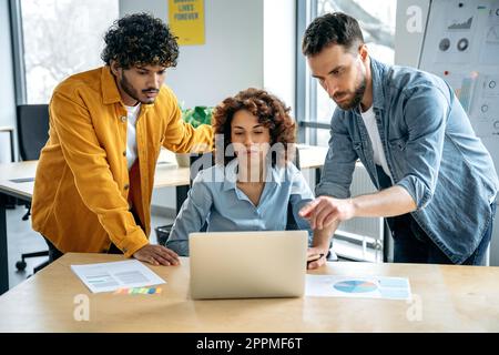 Teamwork, collaboration. Successful focused multiracial people, creative business team, are working together on a project in a modern office, discussing ideas, brainstorming, analyzing results Stock Photo