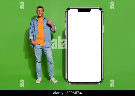 Full length image of confident young male recommend phone application program isolated on green color background Stock Photo