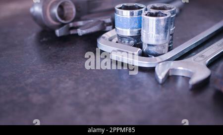 Hand tools consisting of wrenches, pliers, socket wrenches, laid out on old steel plate background. Stock Photo