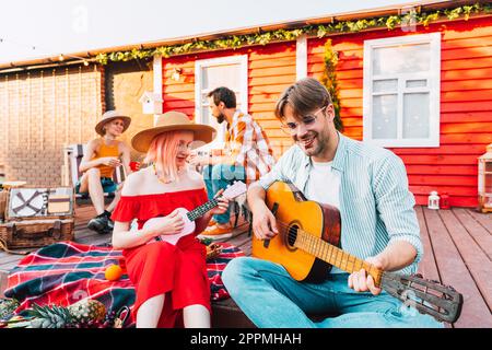 Friends have a picnic and play with guitar Stock Photo