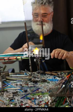 Glassworker while shaping the glass with a very high temperature flame Stock Photo