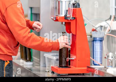 capping beer bottles on a machine in a brewery Stock Photo