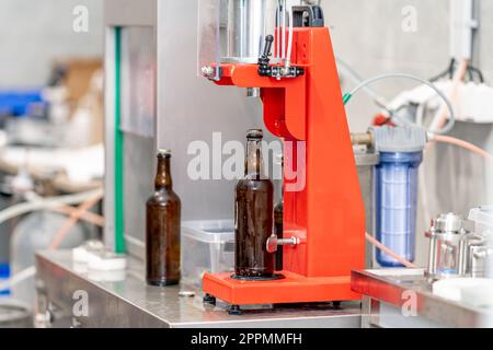 capping beer bottles on a machine in a brewery Stock Photo