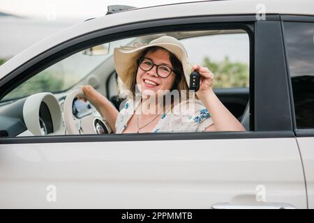 Car driver woman smiling showing new car keys and car. Female driving rented cabrio on summer vacation Stock Photo