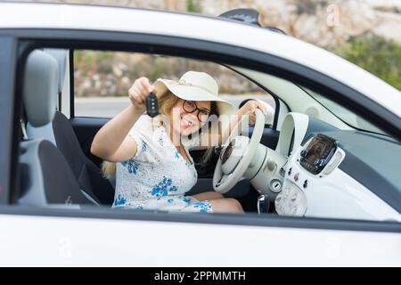Car driver woman smiling showing new car keys and car. Female driving rented cabrio on summer vacation Stock Photo