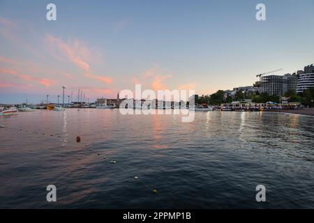 A very beautiful sunset on the pier, a beautiful sky in Budva, Montenegro against the backdrop of a pier with yachts and a resort town. Stock Photo