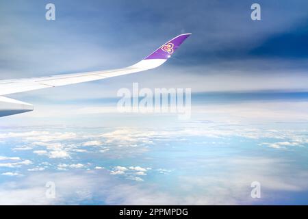 BANGKOK, THAILAND-OCTOBER 19, 2019 : Plane wing of Thai Airways Airlines. Passenger plane. Wing of plane over white fluffy clouds. Airplane flying on blue sky. Scenic view from airplane window. Stock Photo