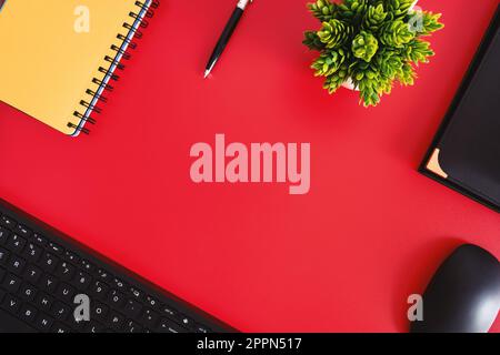 "Red Desk with Essential Tools" - A red flat lay desk with a pen, keyboard, mouse, planner, and potted plant for a productive workspace. Stock Photo