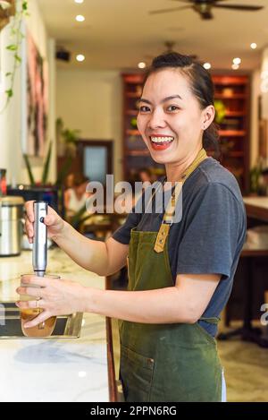 Vietnamese barista using a mixer for condensed milk in glass cup for preparing vietnamese coffee Cafe Sua Stock Photo